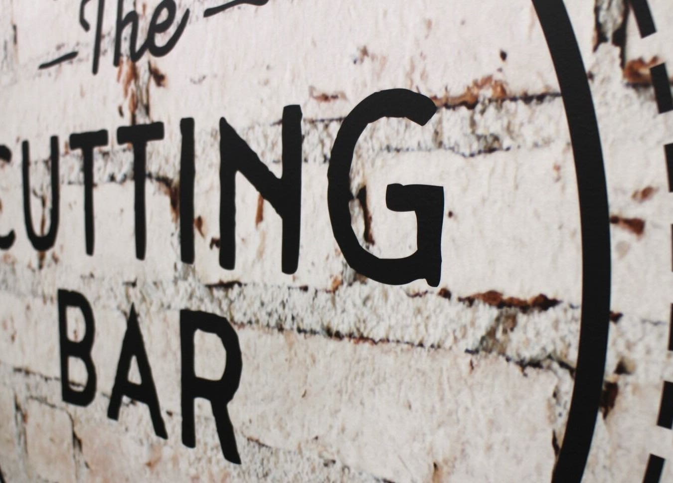 Logo on rustic wall at The Cutting Bar, located in Nelson, Nelson, NZ. A stylish beauty venue.
