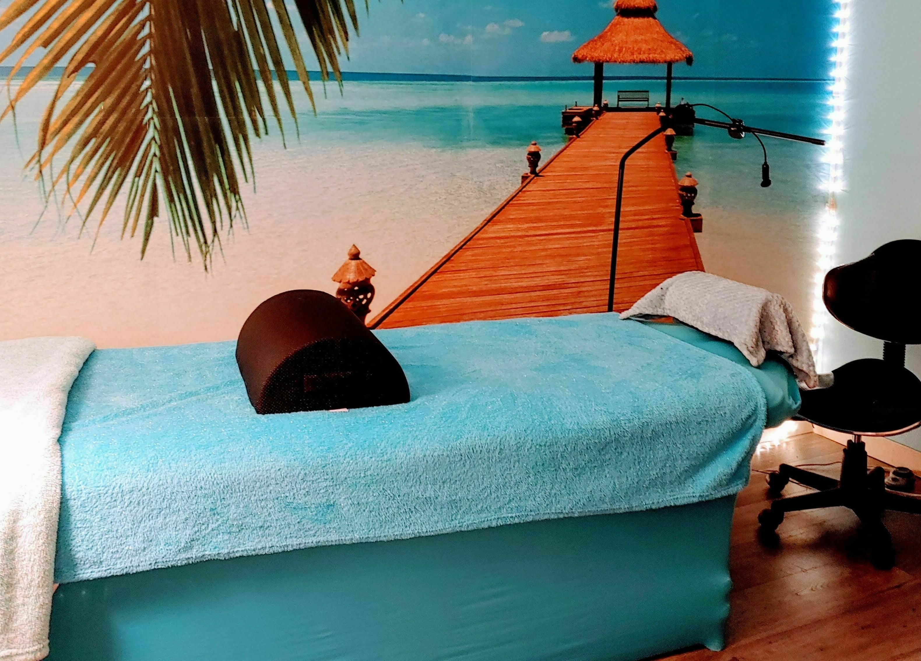 Relaxing massage room at Tropical Escape in Sherrill, New York, US featuring a serene beach mural.