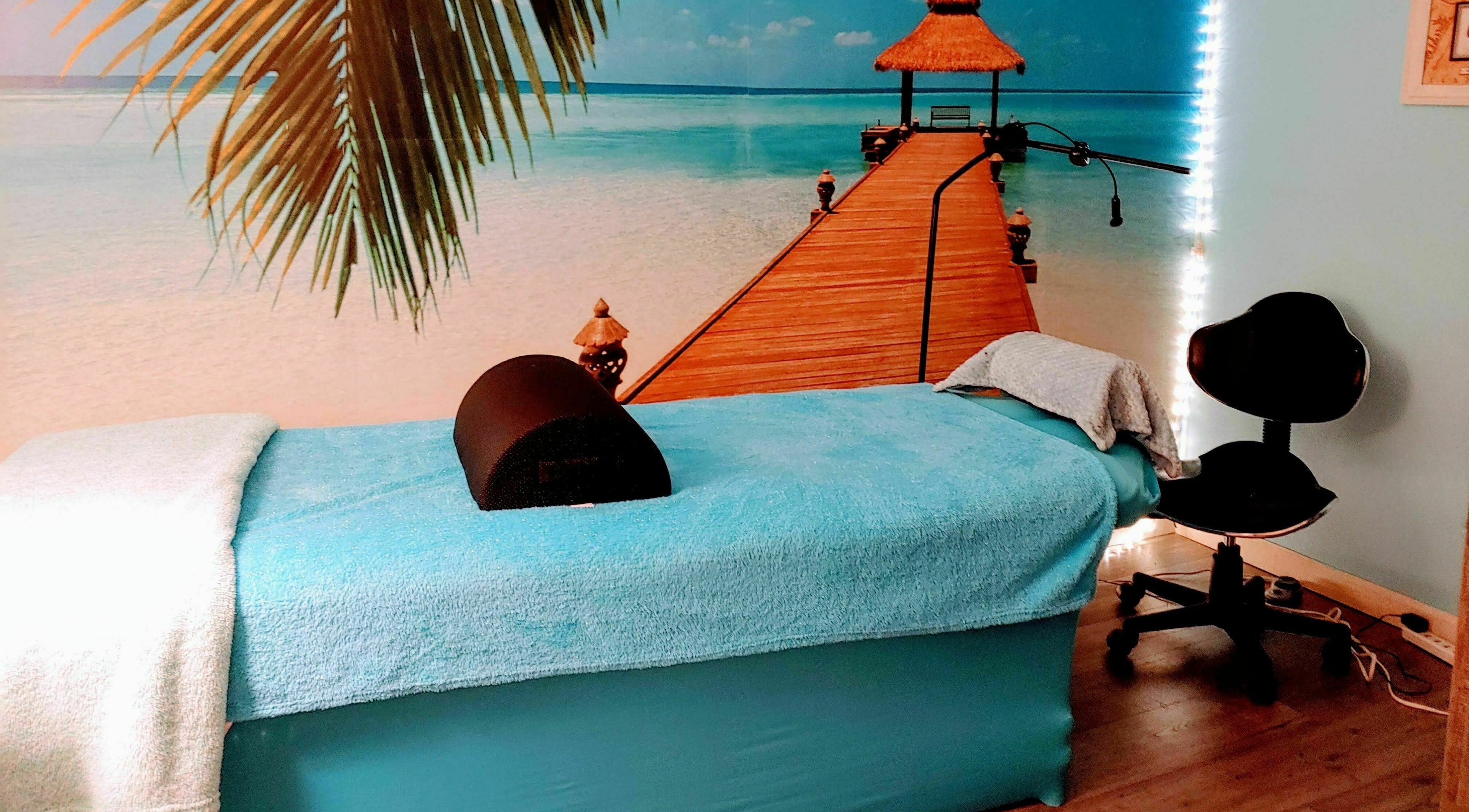 Relaxing massage room at Tropical Escape in Sherrill, New York, US featuring a serene beach mural.