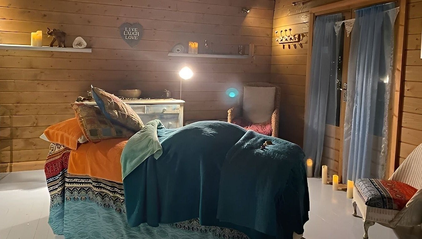Cozy treatment room at Touching Lives in Hampton, England, GB, with soothing lighting and wooden decor.