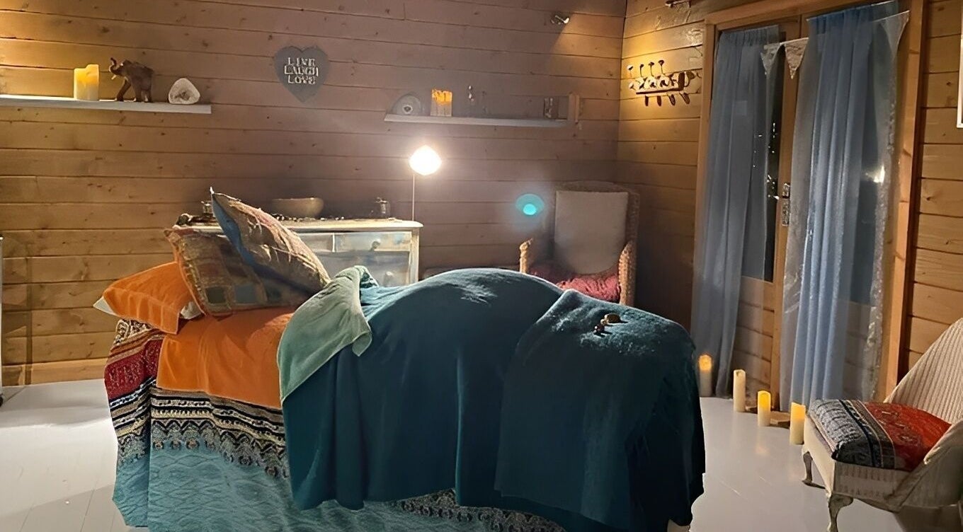 Cozy treatment room at Touching Lives in Hampton, England, GB, with soothing lighting and wooden decor.