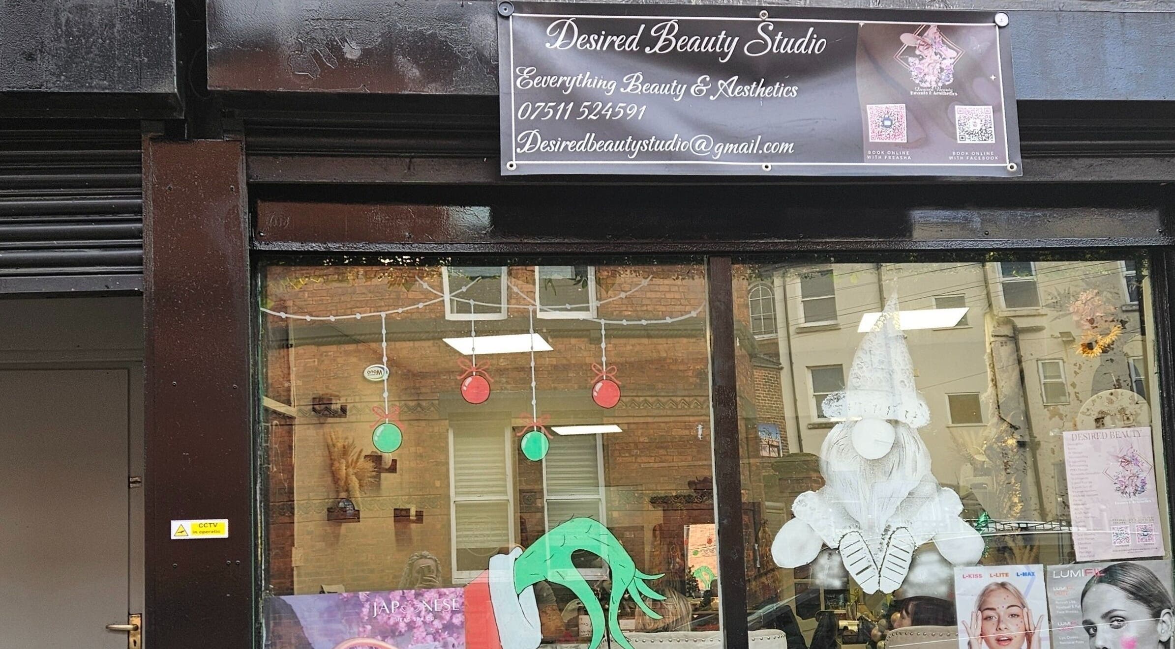 Front window of Desired Beauty, St Helens, England, GB, showcasing festive decor and signage.