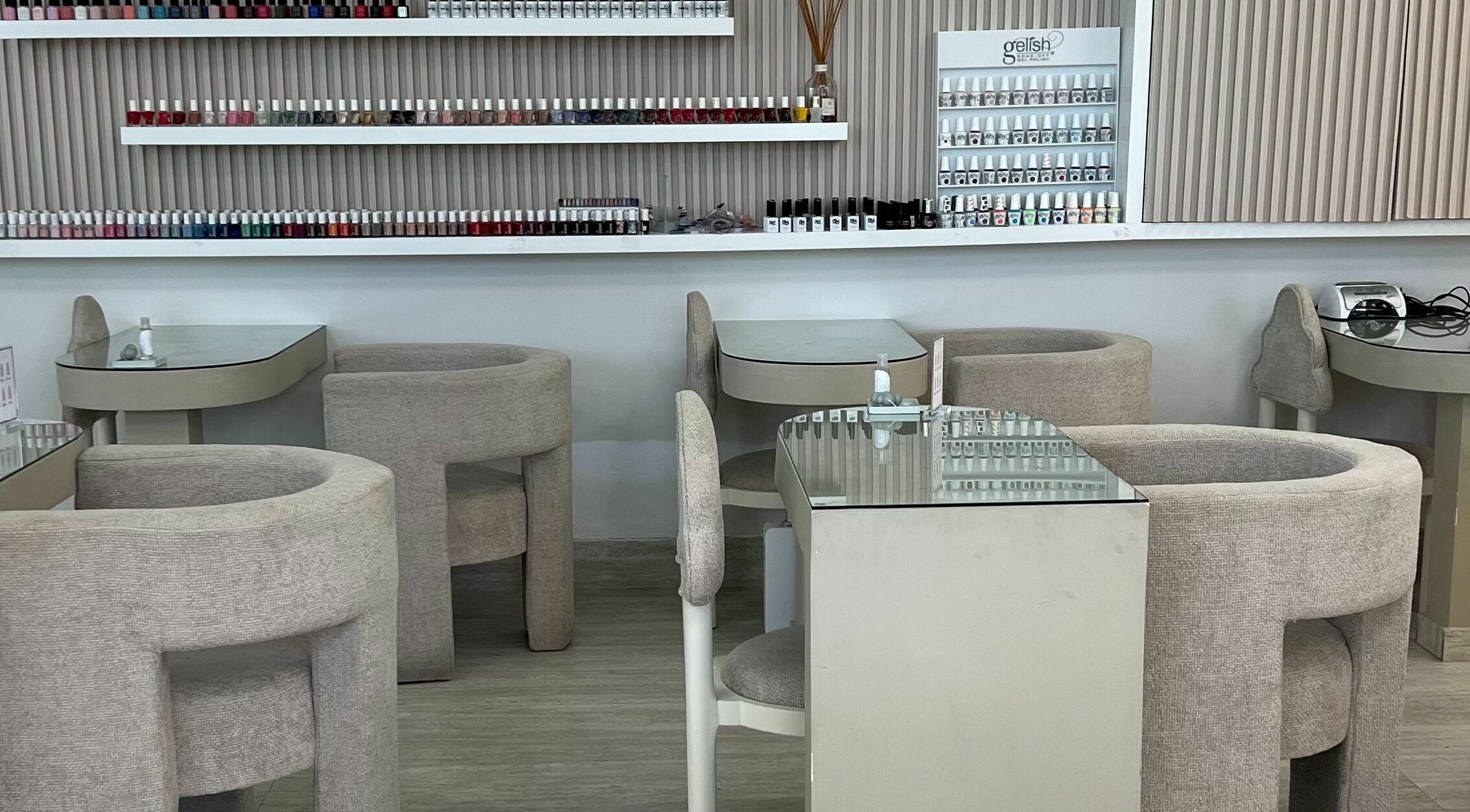 Chic nail salon interior at The Cloud Spa, Abu Dhabi, AE. Features plush seating and extensive nail polish display.