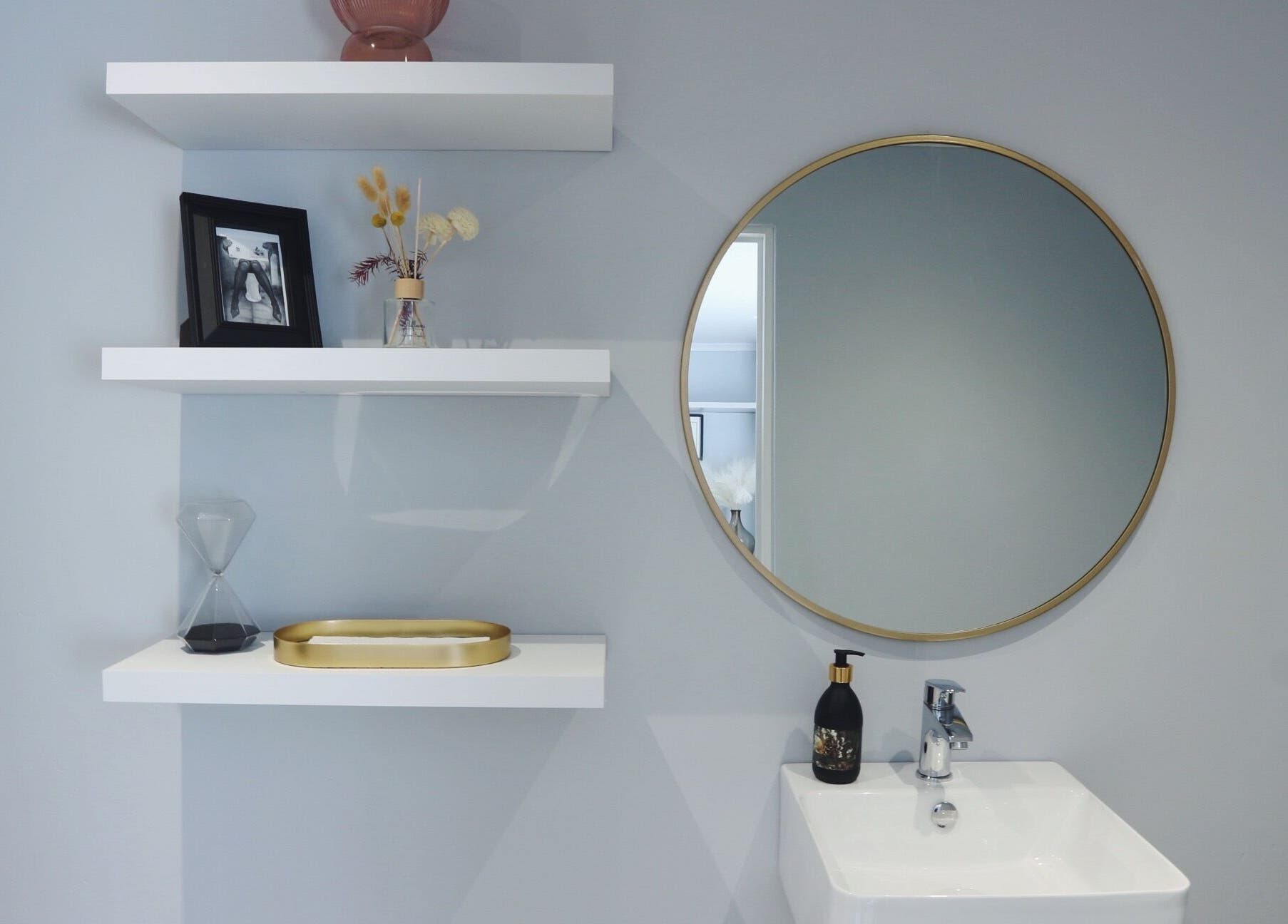 Luxify Laser's stylish restroom features a round mirror and shelves in Cape Town, Western Cape, ZA.