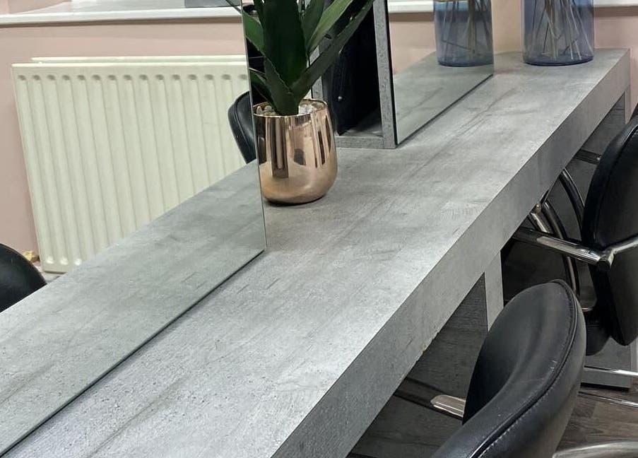 Modern salon table setup at Chique Hair & Beauty, Carlisle, England, GB with chairs and a decorative plant.