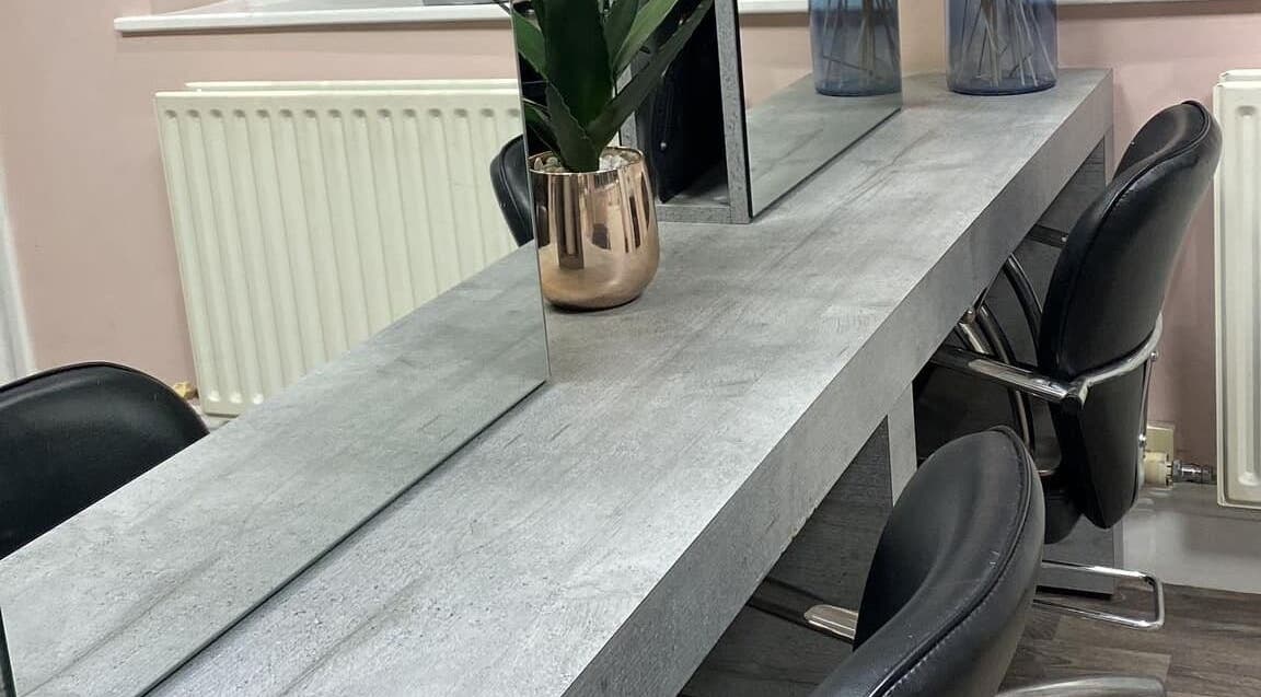 Modern salon table setup at Chique Hair & Beauty, Carlisle, England, GB with chairs and a decorative plant.