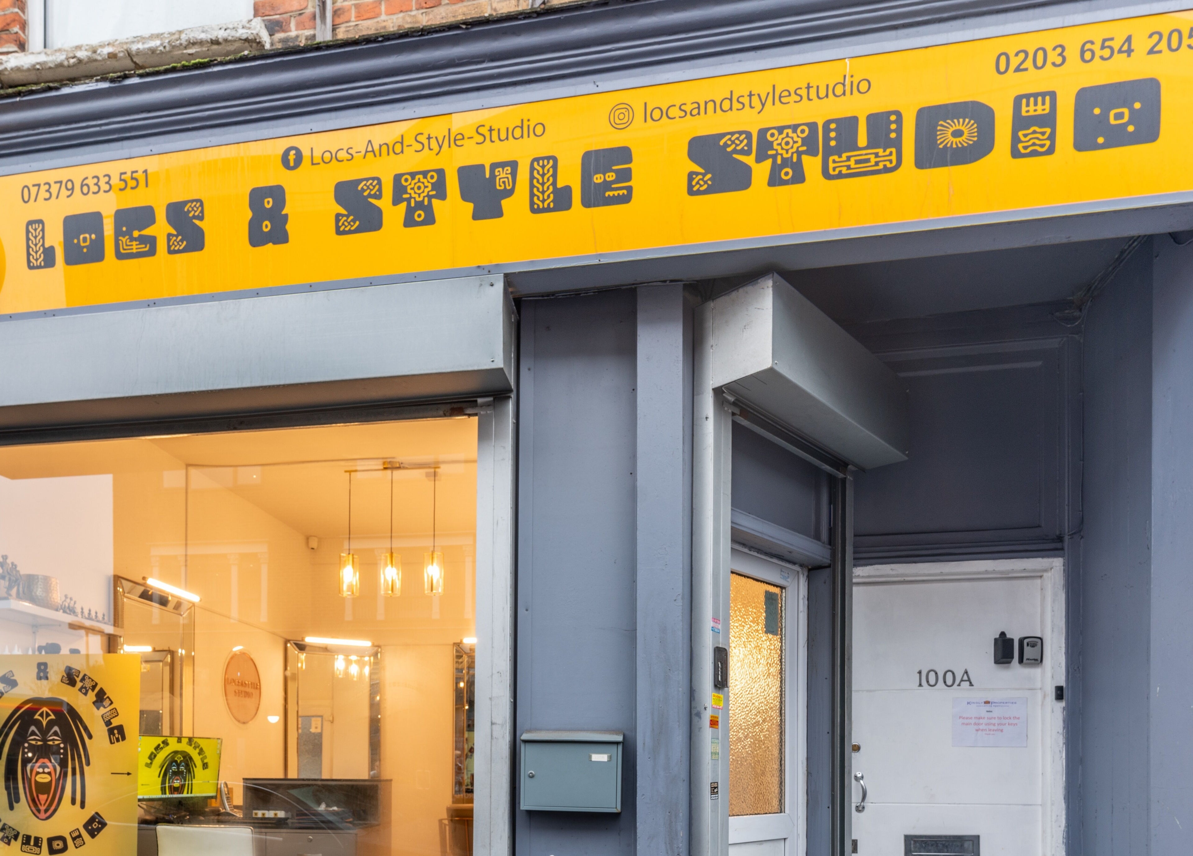 Exterior view of Locks & Style Studio, a beauty venue in London, England, GB featuring a bright yellow sign.