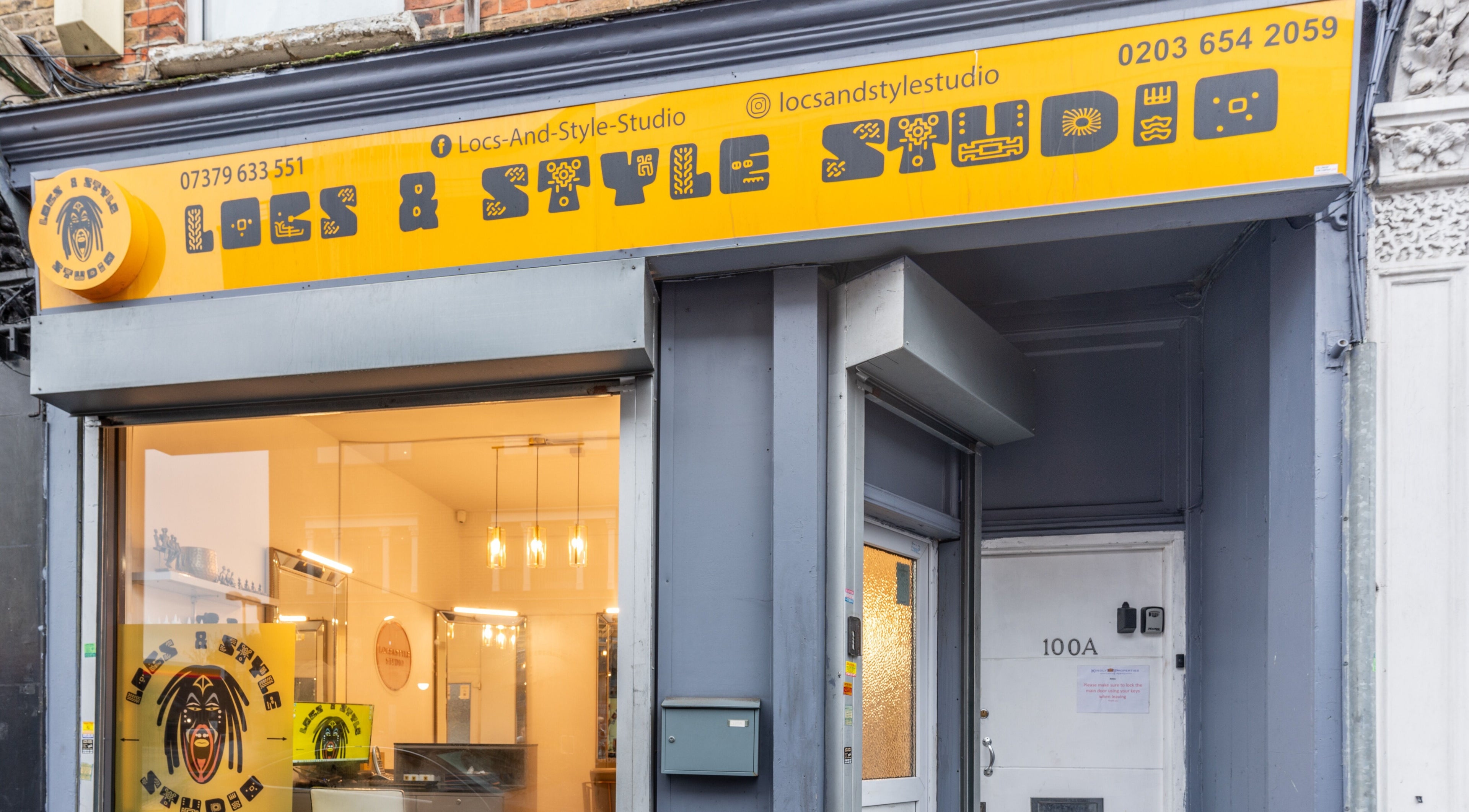 Exterior view of Locks & Style Studio, a beauty venue in London, England, GB featuring a bright yellow sign.