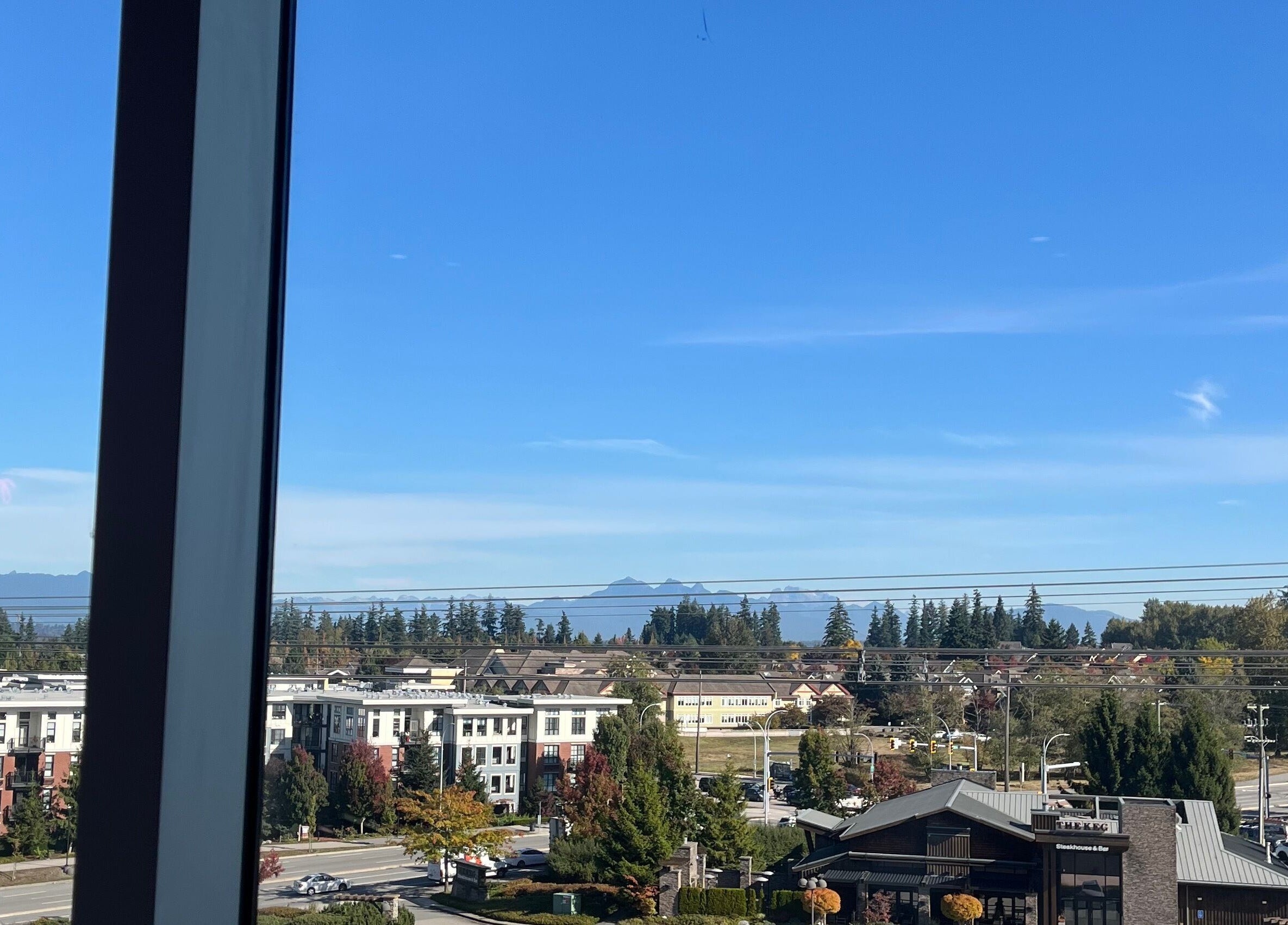View from Refine Manicure Studio Surrey, BC, showcasing mountains and cityscape with clear skies.