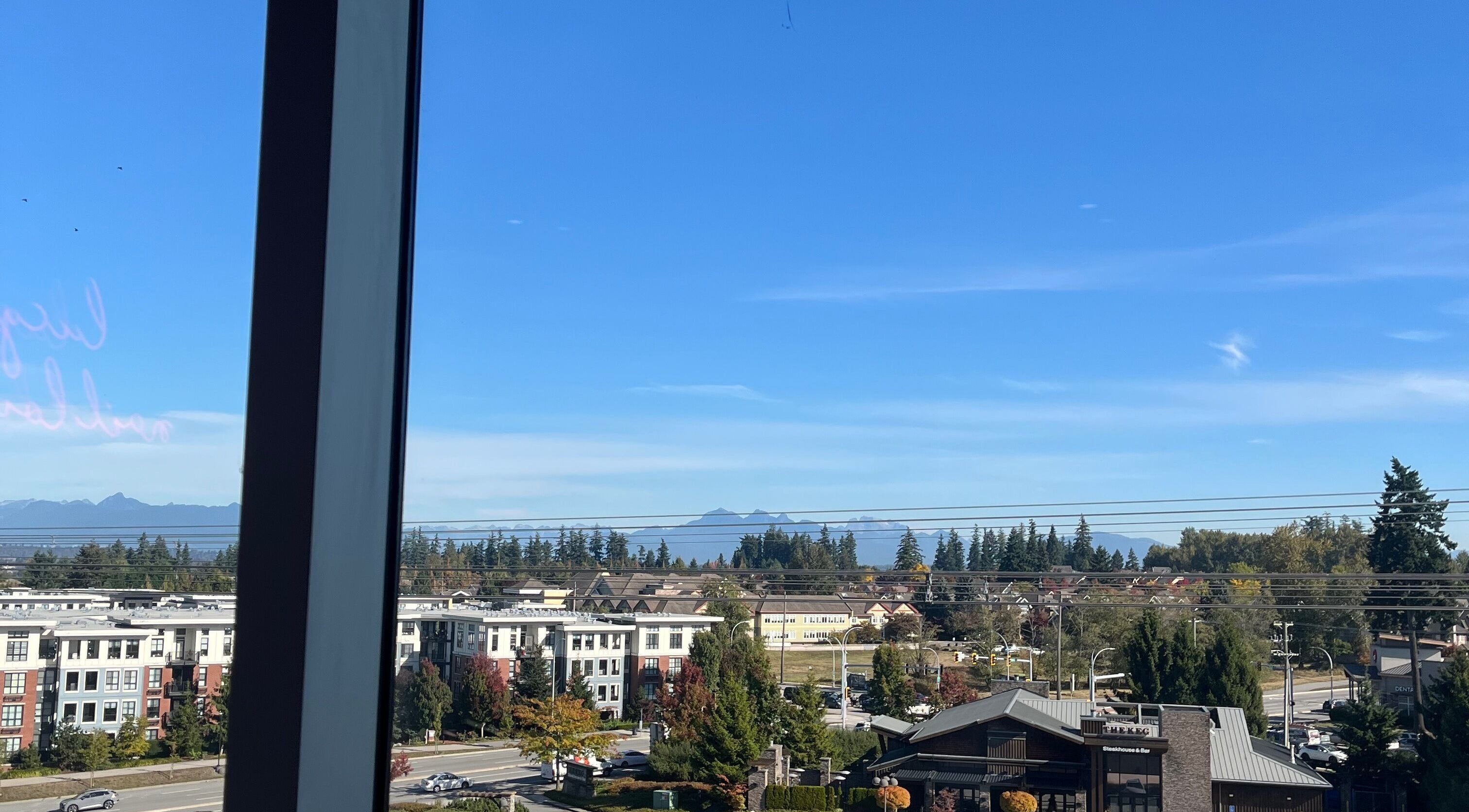 View from Refine Manicure Studio Surrey, BC, showcasing mountains and cityscape with clear skies.