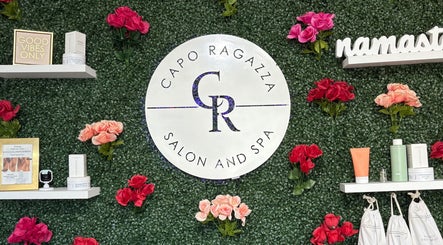 Capo Ragazza Salon and Spa logo on a lush floral wall in Folsom, California, US, with products and decor.