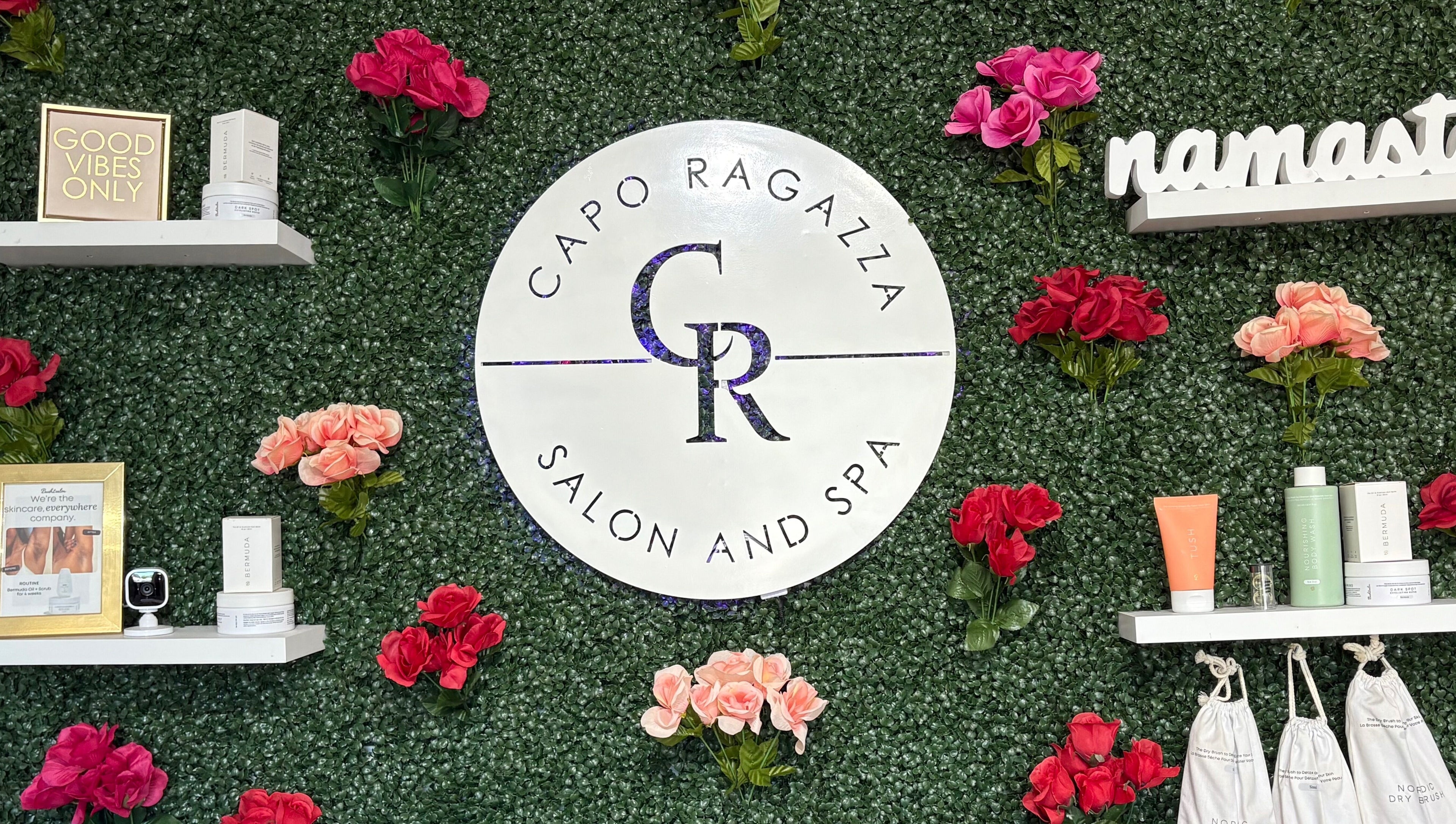 Capo Ragazza Salon and Spa logo with flowers on a lush green wall in Folsom, California, US.