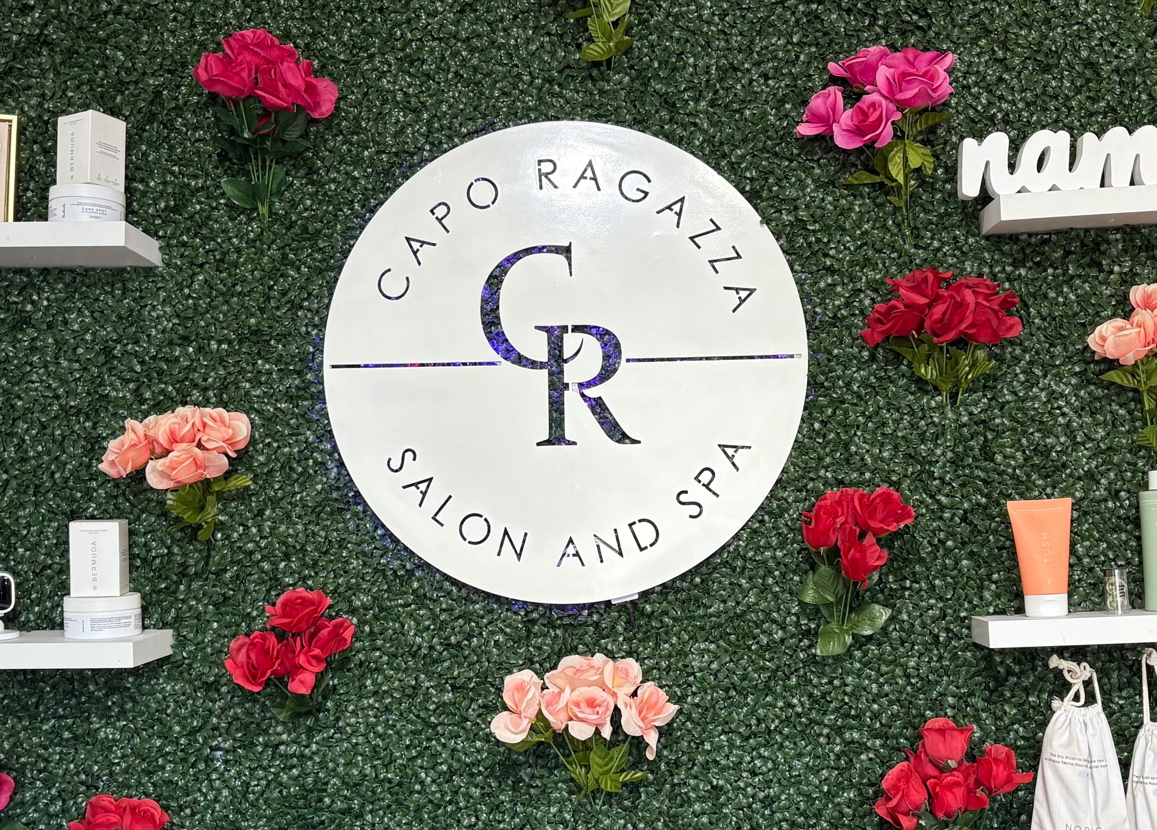Capo Ragazza Salon and Spa logo with flowers on a lush green wall in Folsom, California, US.