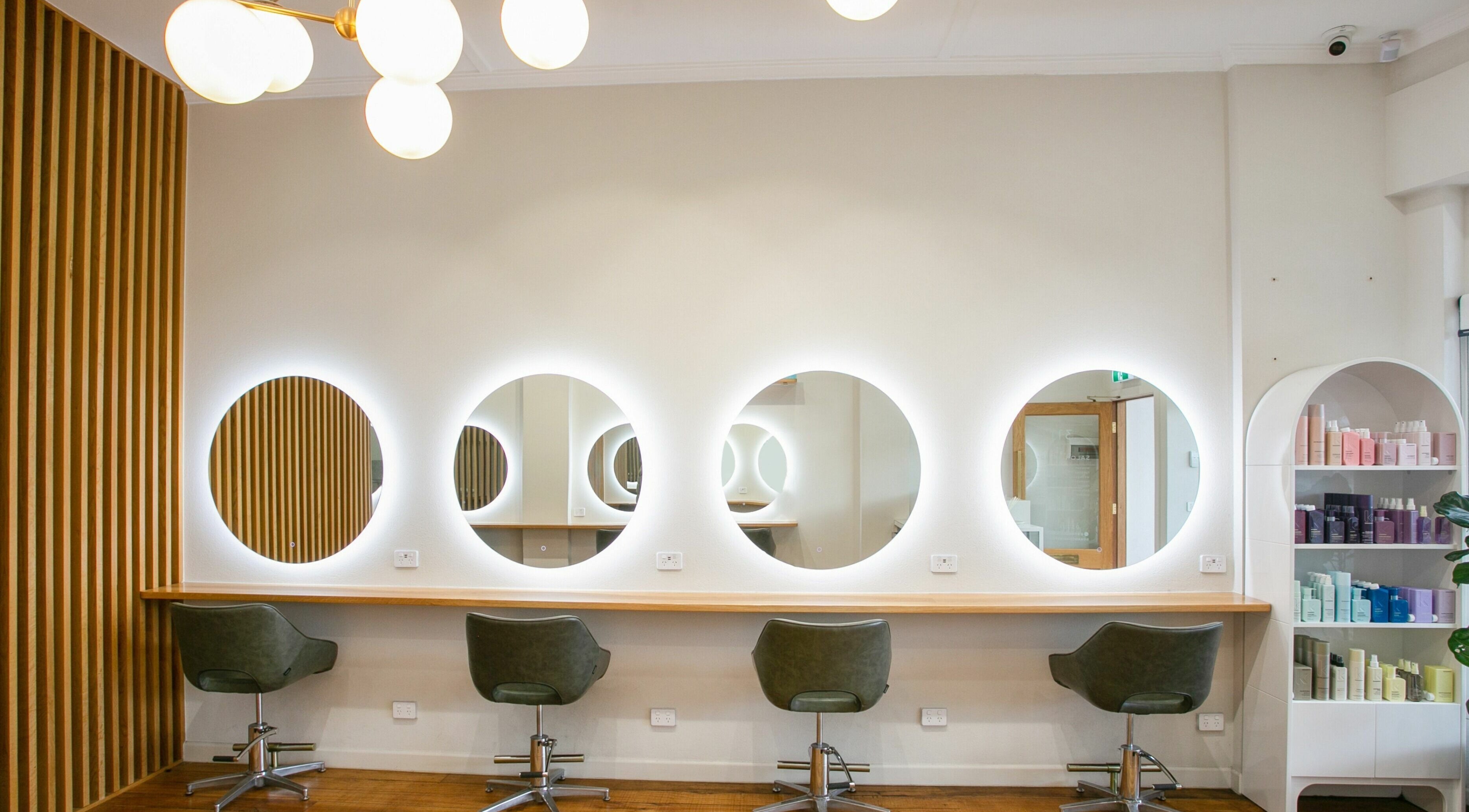 Modern styling stations at Bo & Co Hair Studio in Melbourne, Victoria, AU with round mirrors and chairs.