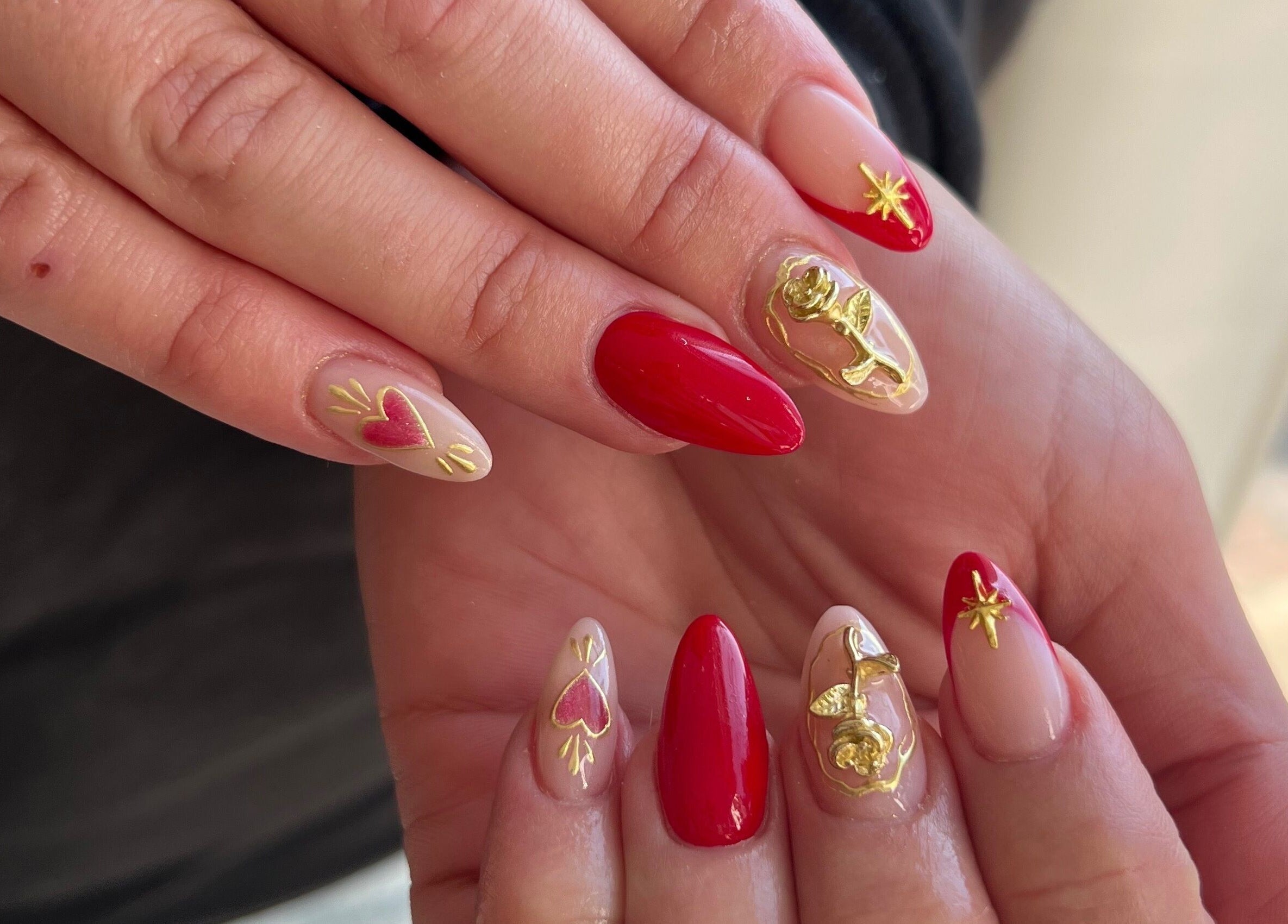 Vibrant red and gold nail art at Beauty by Design, Gqeberha, Eastern Cape, ZA, showcasing intricate designs.