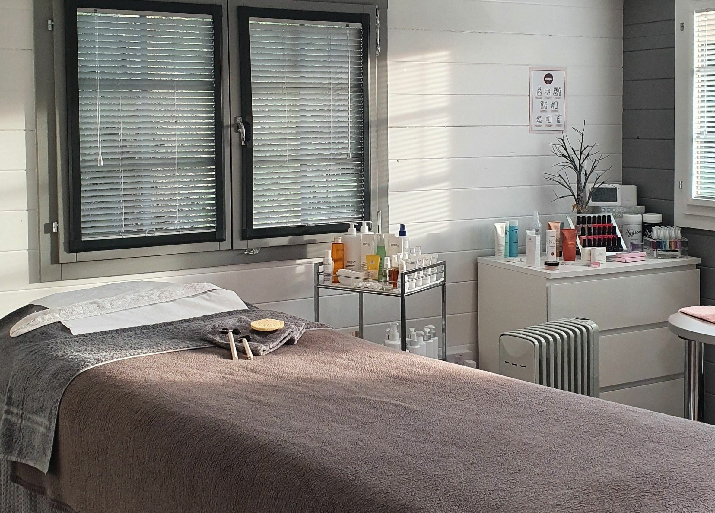 Tranquil treatment room at Beautopia, BANFF, GB, featuring a cozy massage bed and skincare products.