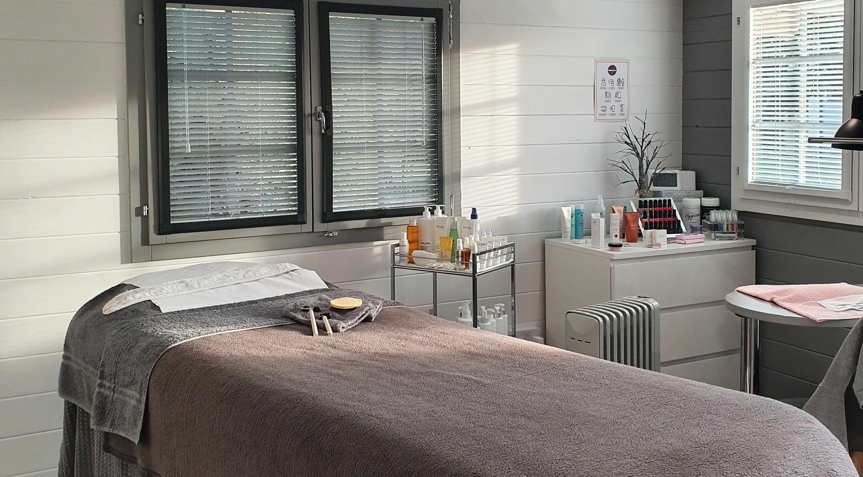 Tranquil treatment room at Beautopia, BANFF, GB, featuring a cozy massage bed and skincare products.