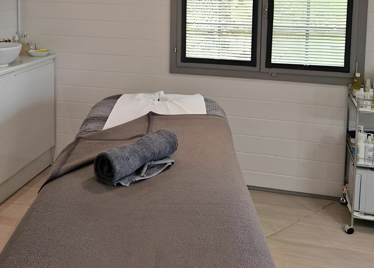 Calm treatment room at Beautopia, BANFF, GB, with massage table, towels, and skincare products.