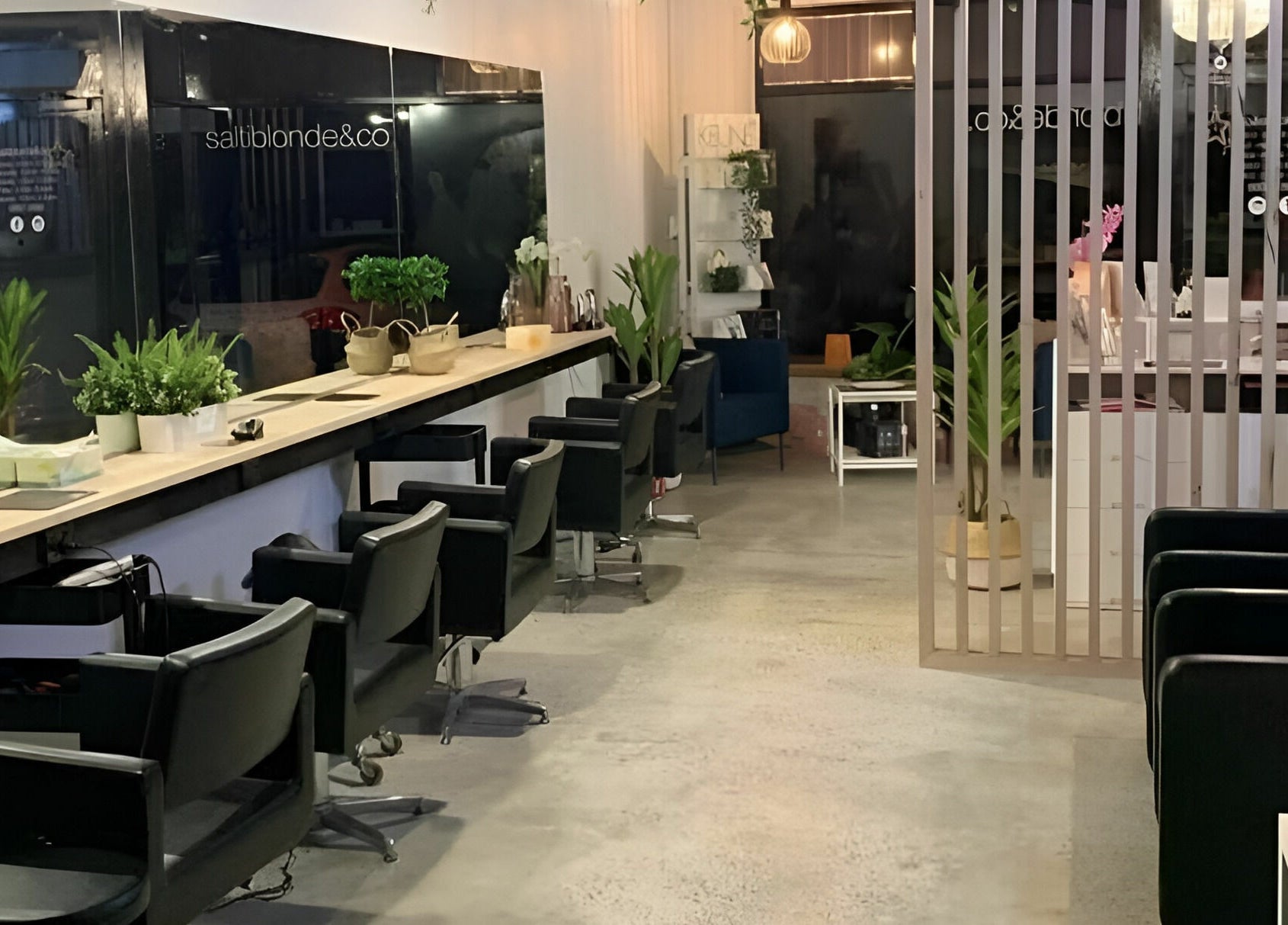 Modern salon setup at Salti Blonde and Co. in Melbourne, Victoria, AU, featuring sleek chairs and lush plants.
