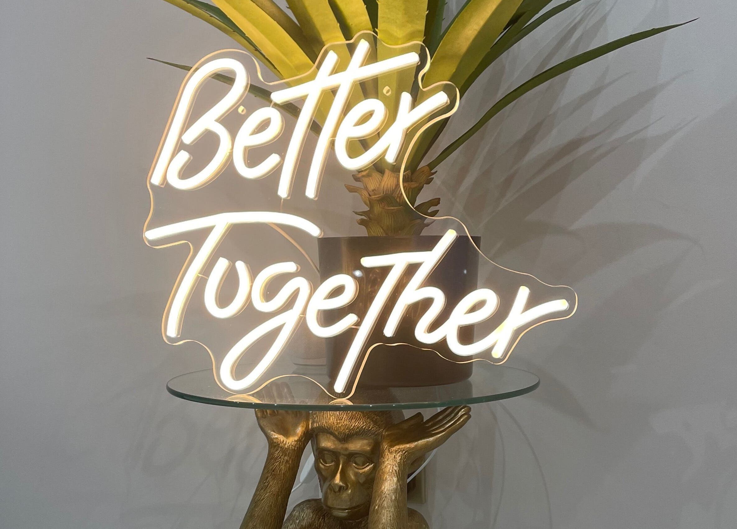 Neon sign 'Better Together' at 11:11 Studios, Leicester, England, GB, above a decorative monkey sculpture.