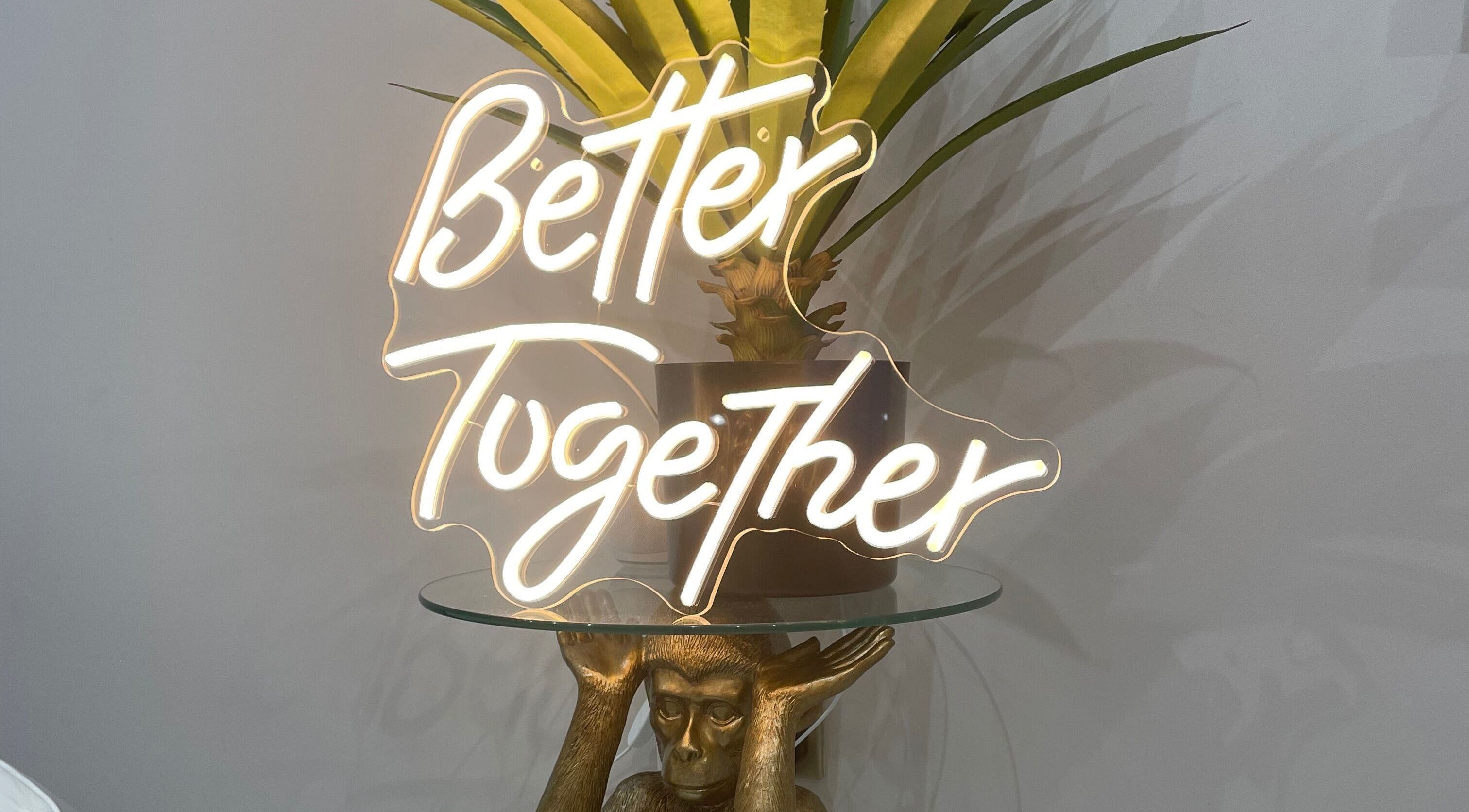 Neon sign 'Better Together' at 11:11 Studios, Leicester, England, GB, above a decorative monkey sculpture.