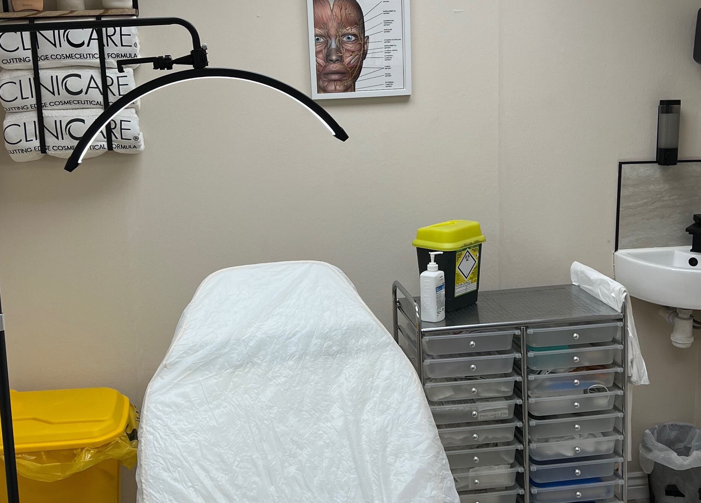 Calm treatment room at DermaLush Aesthetics, Normanton, England, GB. Features a clinical bed and tool storage.