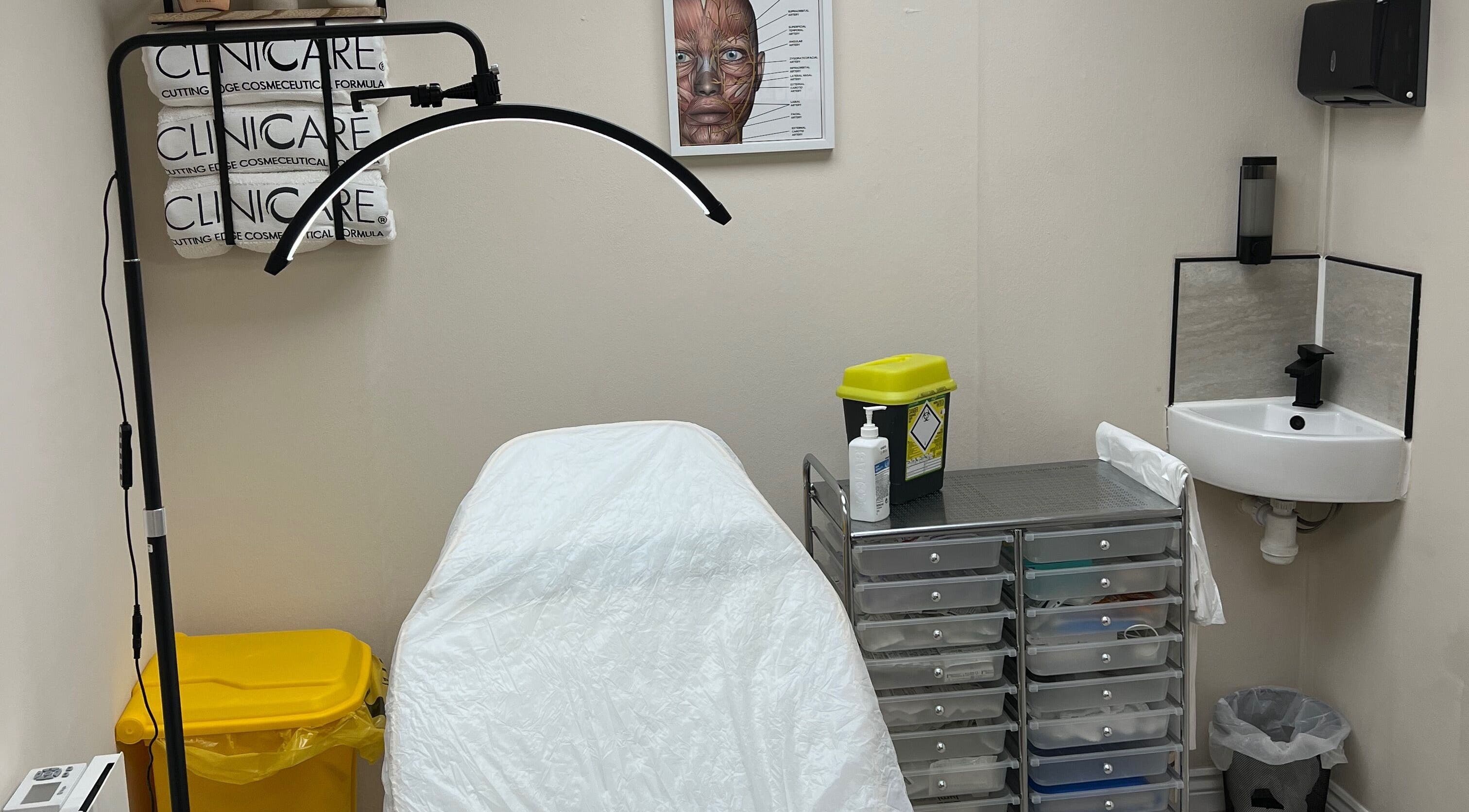 Calm treatment room at DermaLush Aesthetics, Normanton, England, GB. Features a clinical bed and tool storage.