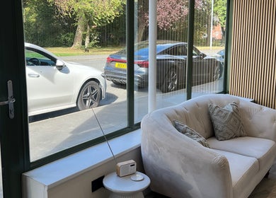 Cozy lounge area at DermaLush Aesthetics, Normanton, England with large windows and a white sofa.