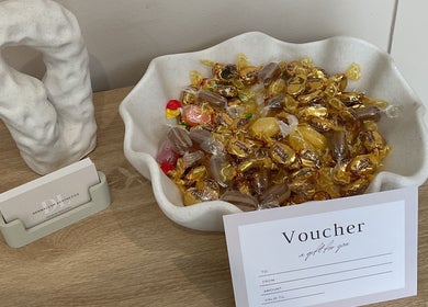 A bowl of colorful candies beside a voucher at DermaLush Aesthetics, Normanton, England, GB.