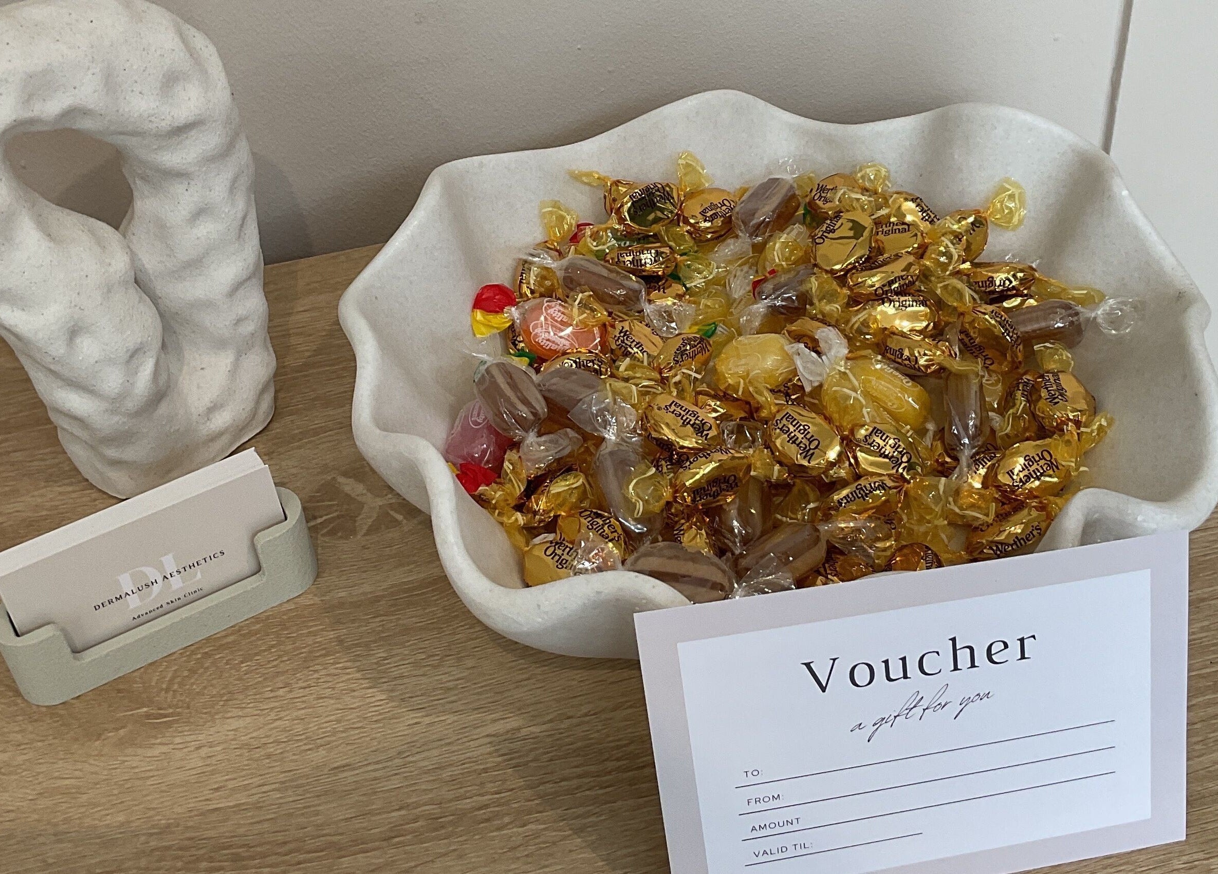 Candy bowl and voucher at DermaLush Aesthetics, Normanton, England, GB. Inviting touch for wellness visitors.