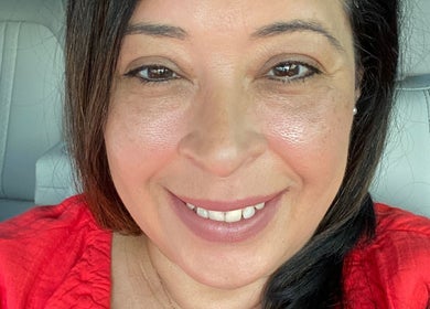 Maria Rodriguez - Aesthetician in Millsboro, Delaware, US, smiling warmly in a red top.