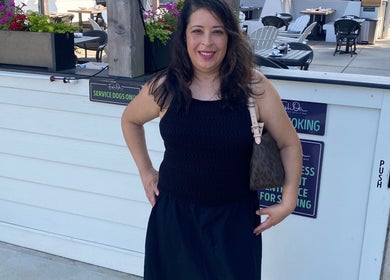 Maria Rodriguez - Aesthetician smiling at Millsboro, Delaware venue entrance.