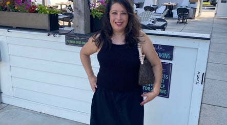 Maria Rodriguez - Aesthetician smiling at Millsboro, Delaware venue entrance.