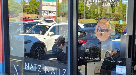 Entrance of Natz Nailz and Beauty with reflections of parked cars in Parkwood, Queensland, AU.