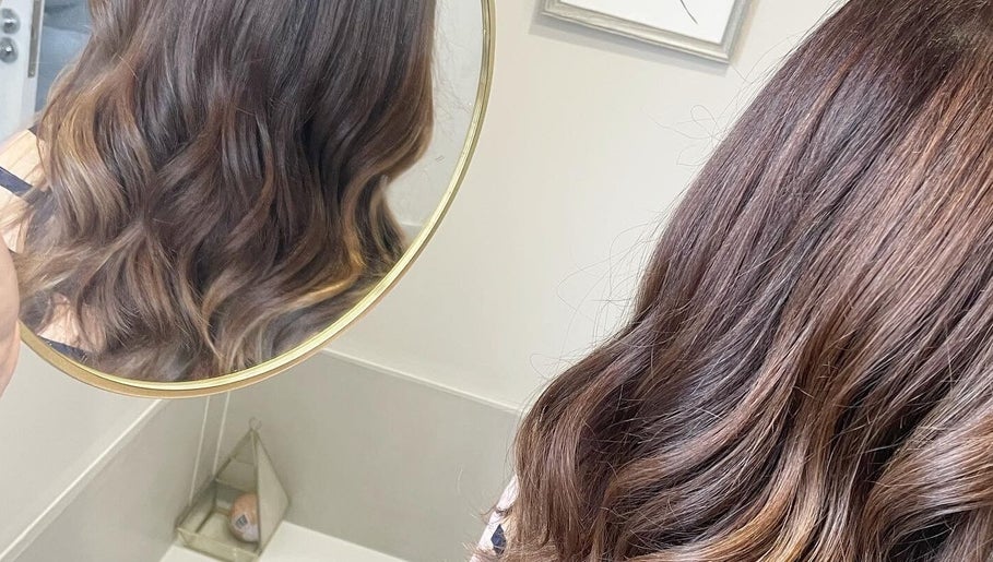 Elegant wavy hairstyle at Laura Waterworth Hair, Dunmurry, Northern Ireland, GB, reflected in circular mirror.