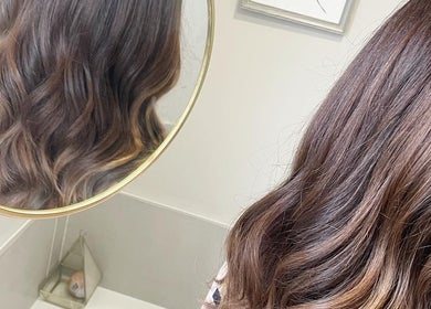 Elegant wavy hairstyle at Laura Waterworth Hair, Dunmurry, Northern Ireland, GB, reflected in circular mirror.