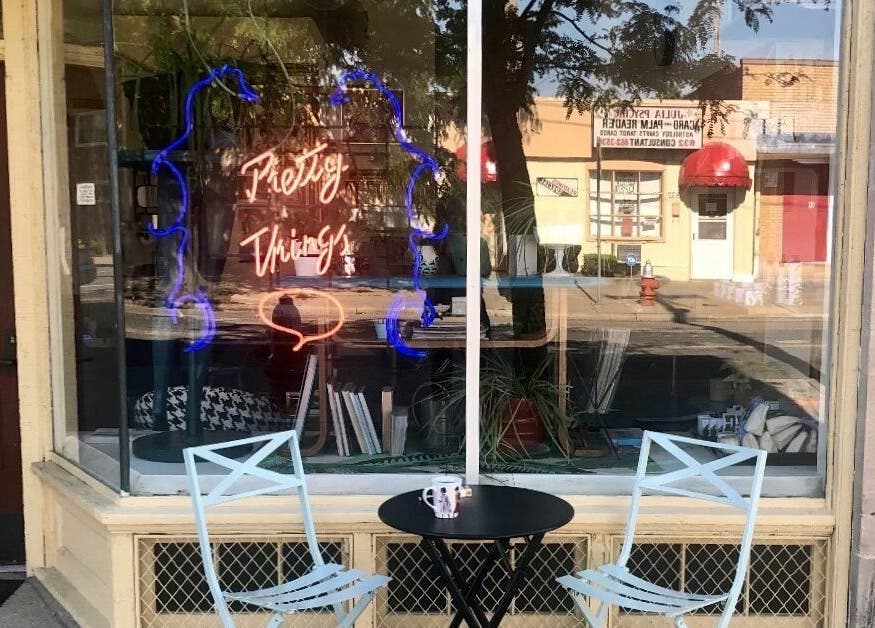 Charming entrance of Pretty Things Salon in Cleveland, Ohio, US, featuring stylish outdoor seating and neon sign.