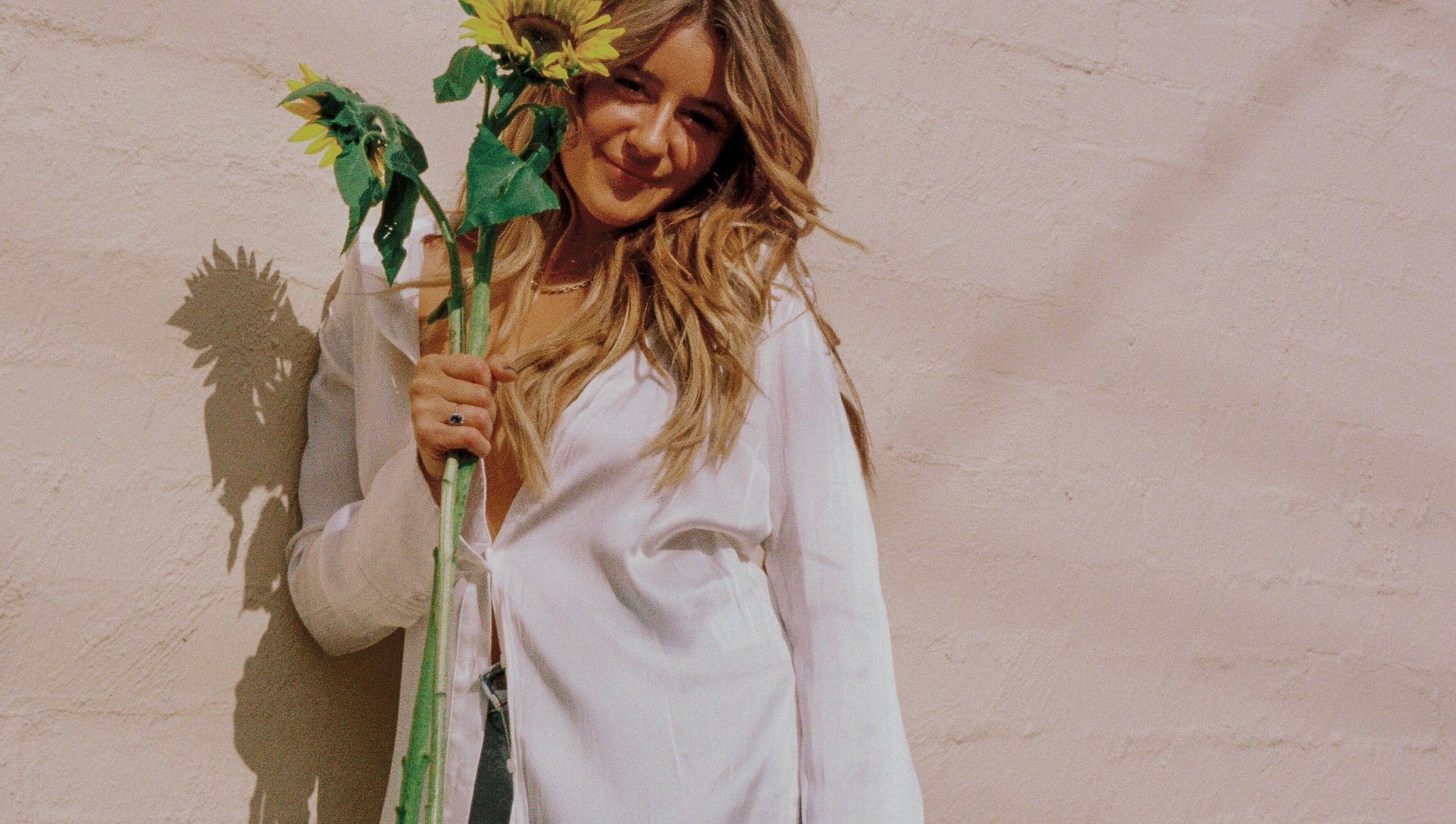Woman smiling with sunflower, highlighting Addie Robins Hair's natural charm in Melbourne, Victoria, AU.