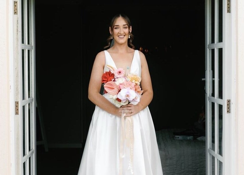 Bride stands with bouquet at Tash's Tanning, Beldon, Western Australia, AU. Elegant entrance for special occasions.