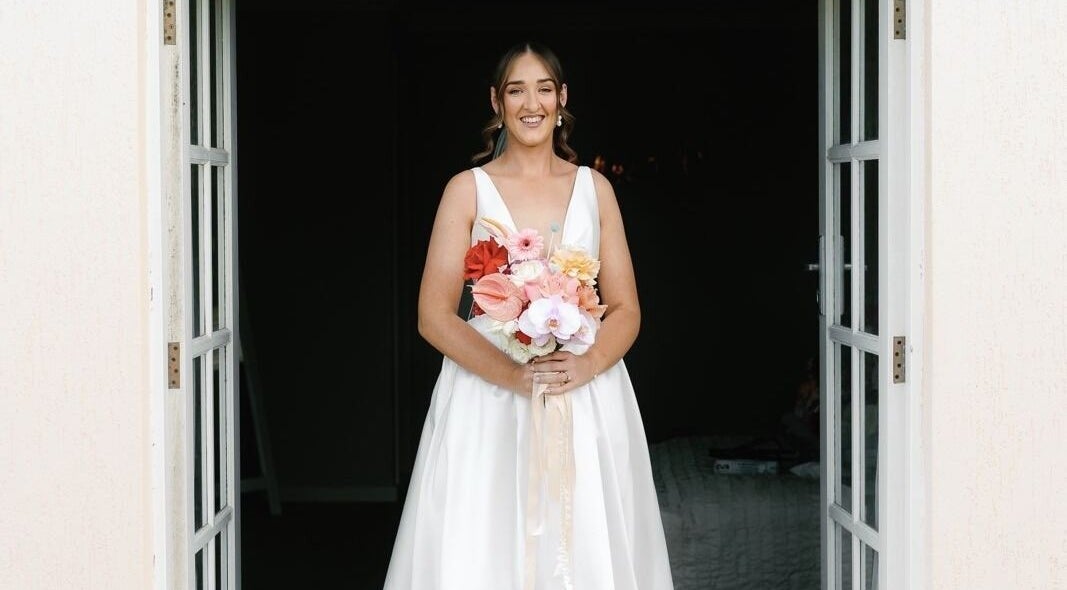 Bride stands with bouquet at Tash's Tanning, Beldon, Western Australia, AU. Elegant entrance for special occasions.