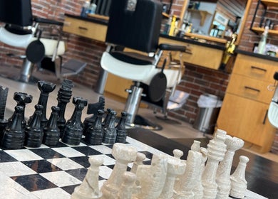 Chess set in a stylish setting at Papito Barbershop, Dubai, Dubai, AE with modern barber chairs in the background.