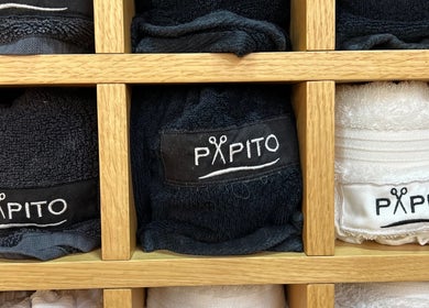 Neatly folded Papito Barbershop towels in a wooden shelf at Dubai, Dubai, AE.