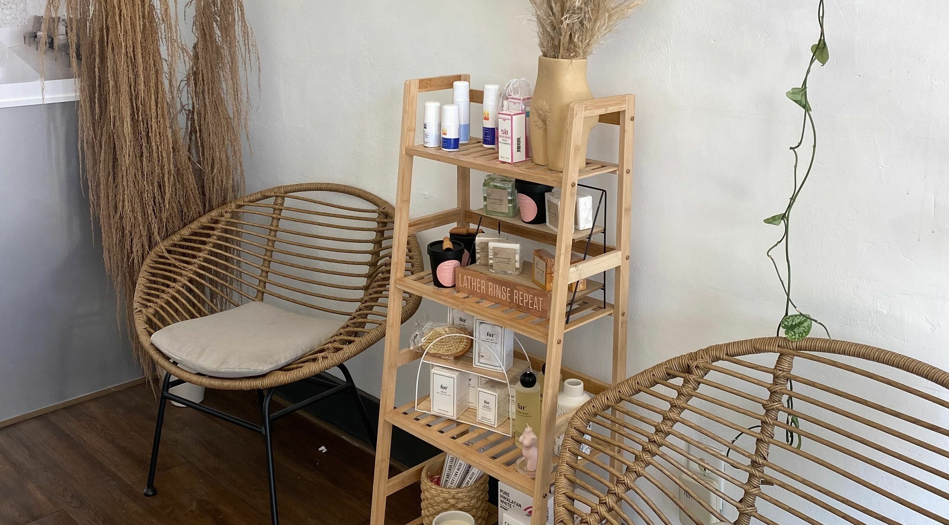 Relaxing corner at Daisy's House of Beauty, Long Beach, California US, featuring wicker chairs and a display shelf.