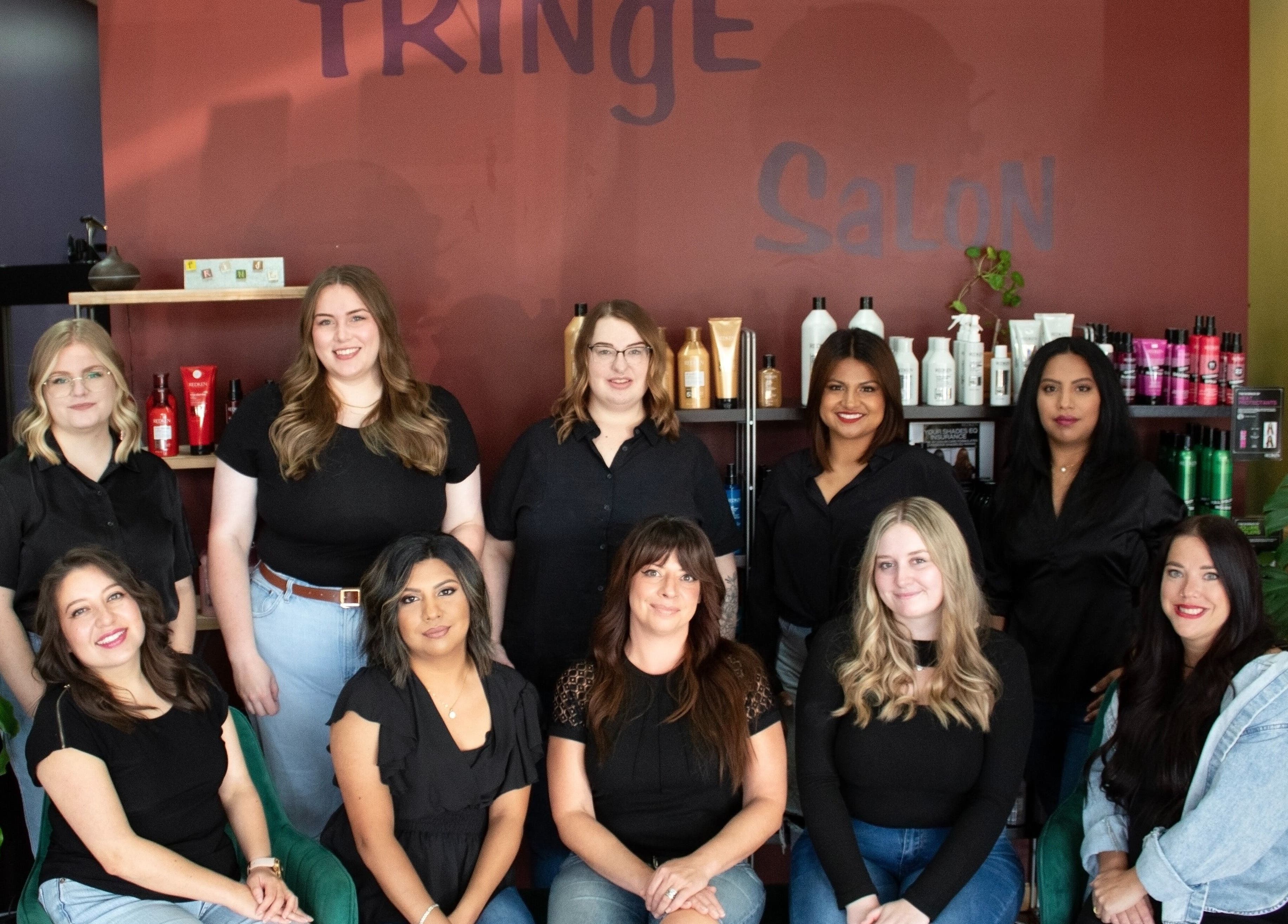 Team of stylists at Fringe Salon in Elkhart, Indiana, US, surrounded by products and greenery.