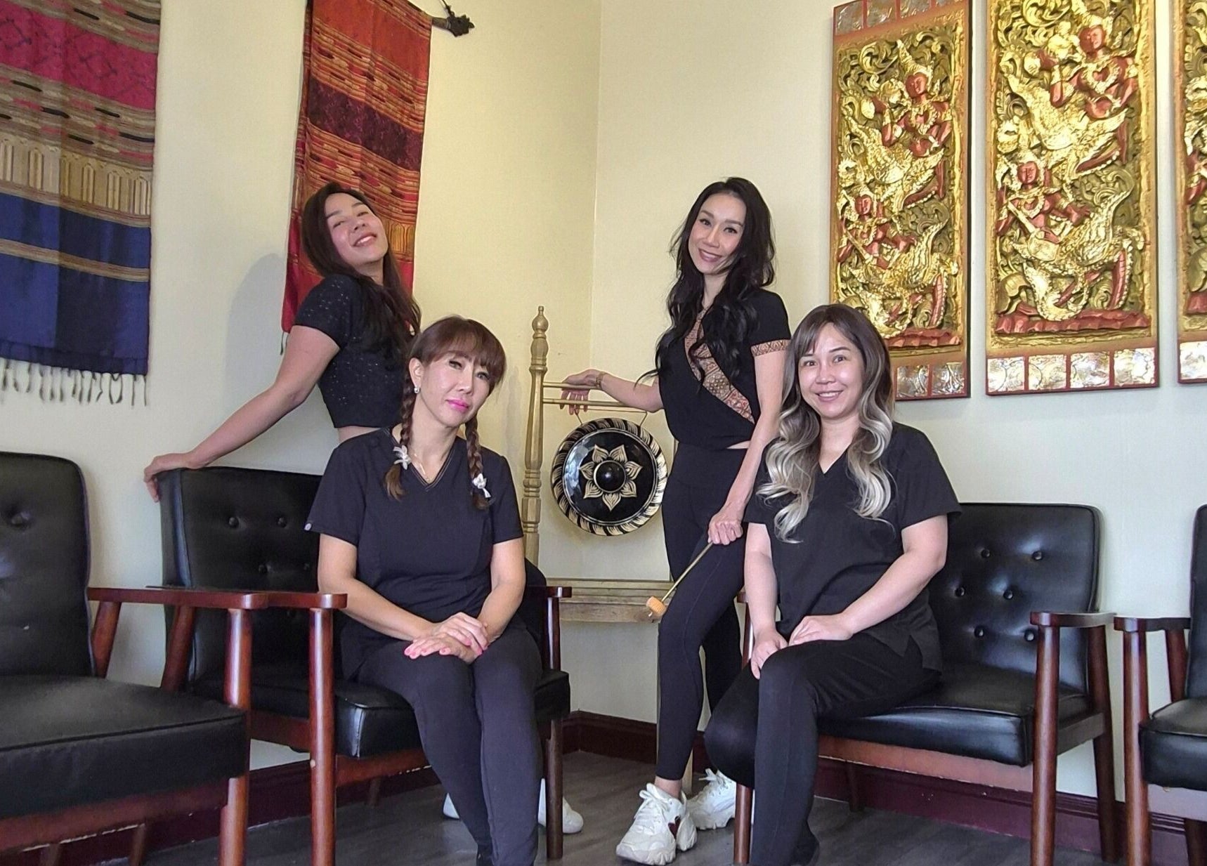 Staff at Chiang Mai Thai Spa in Las Vegas pose in a tranquil, decorated lounge area.