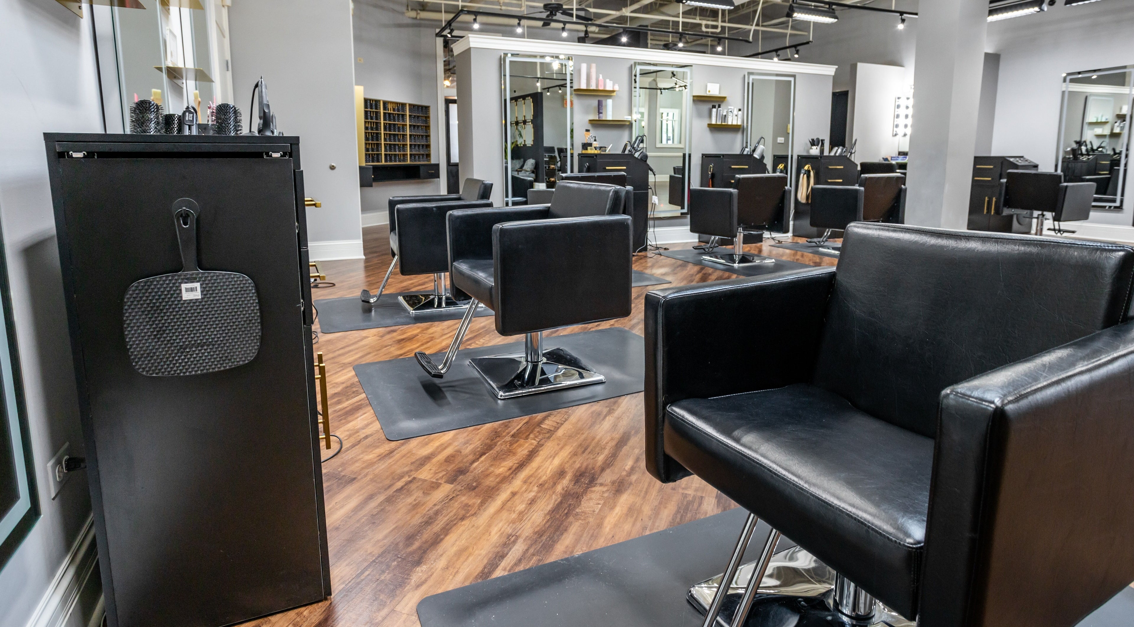 Modern salon interior at Gold and Ash Hair Salon, Palatine, Illinois, US, featuring sleek black chairs and mirrors.