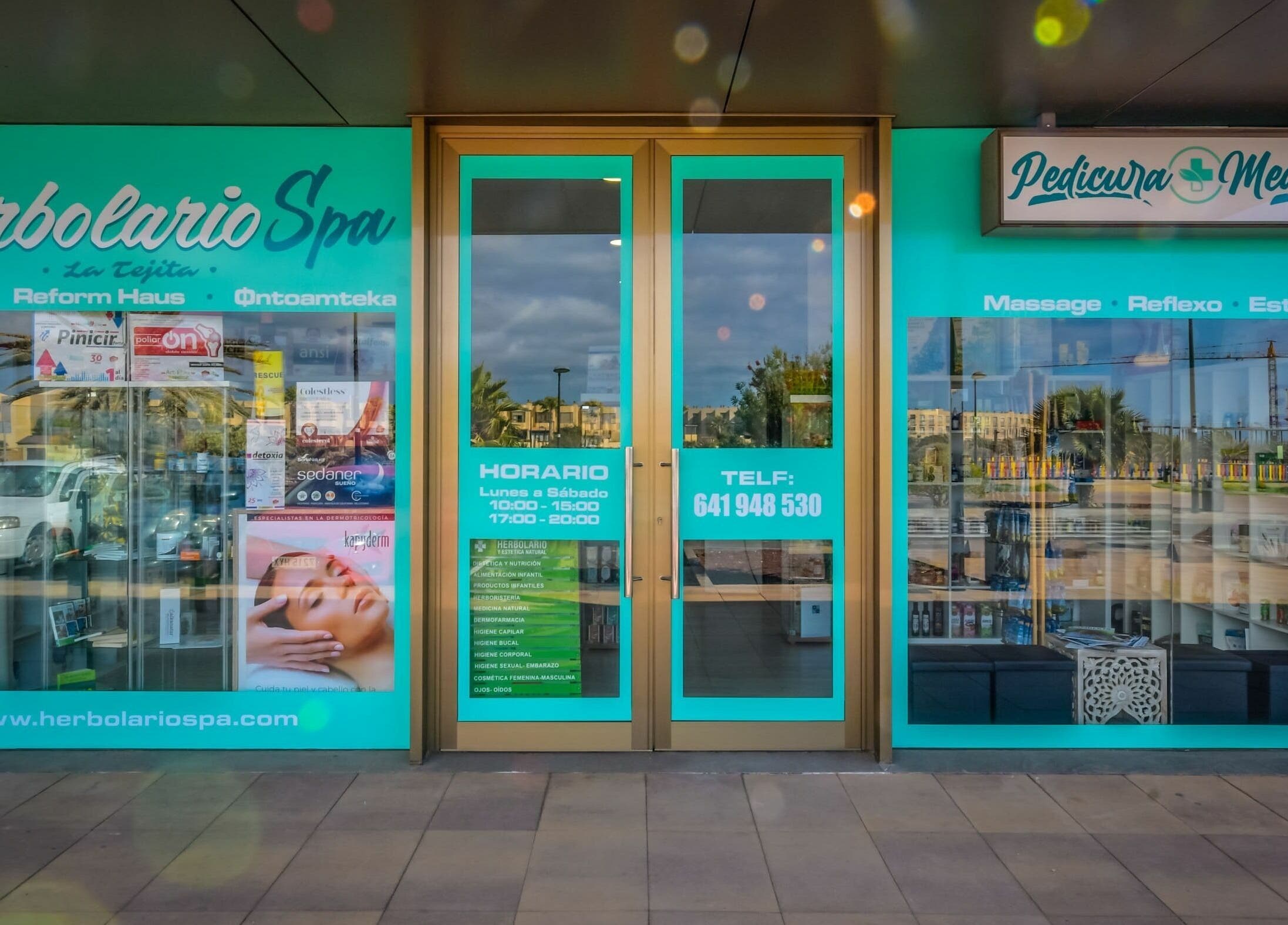 Entrada de Herbolario Spa en La Tejita, Canarias, ES con carteles de servicios de belleza y bienestar.