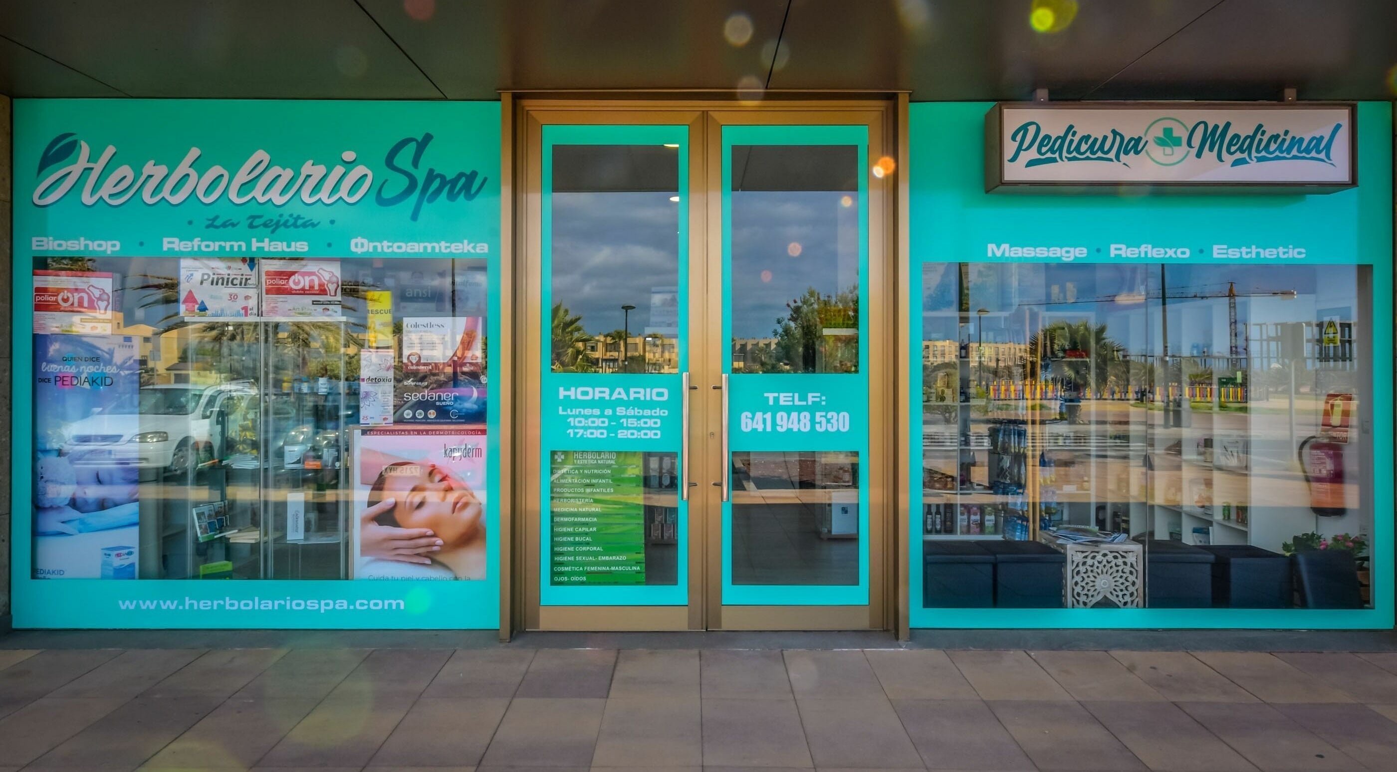 Entrada de Herbolario Spa en La Tejita, Canarias, ES con carteles de servicios de belleza y bienestar.