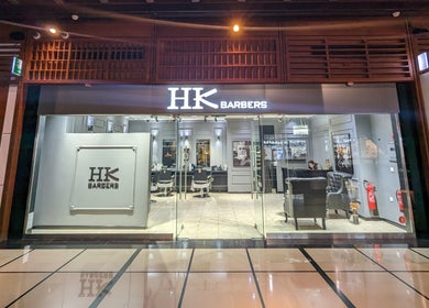 Front view of Hk Barbers at WTC Mall AD, Abu Dhabi. Modern interior with chairs and decor.