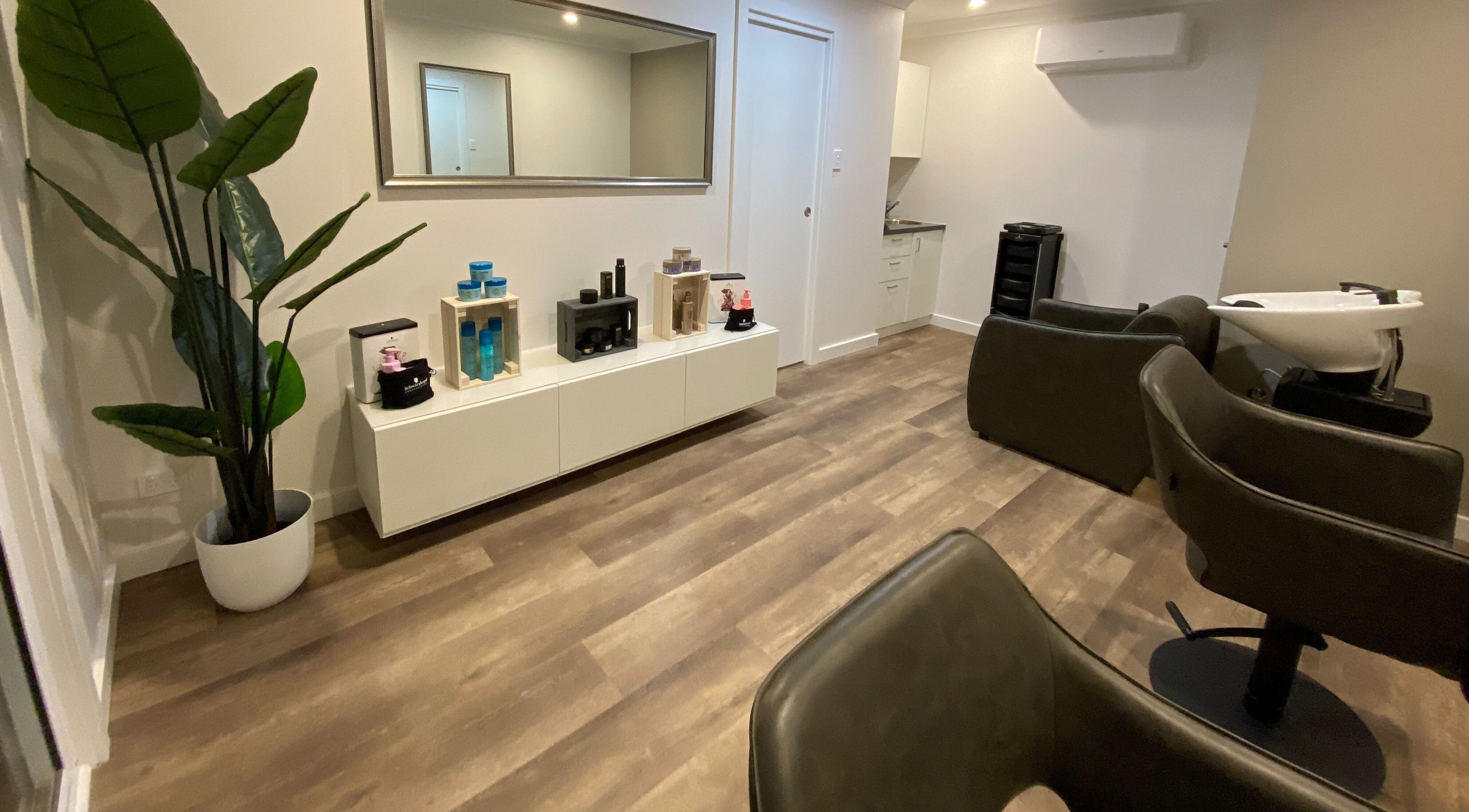 Modern salon interior at Hair at HQ, Menai, New South Wales, AU with stylish chairs and hair products.
